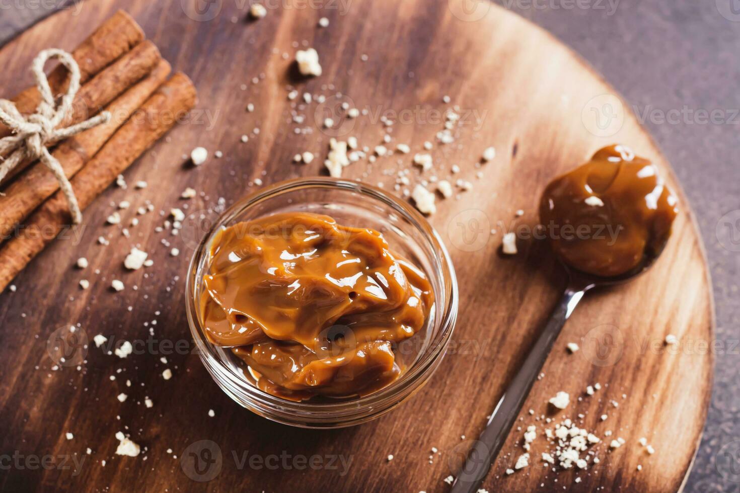 Boiled condensed milk in a glass bowl and cinnamon on a board photo