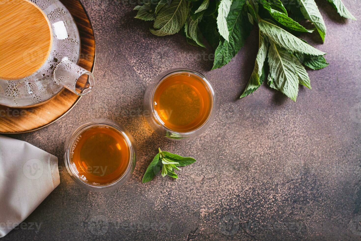 Fresh mint tea in cups and teapot and leaves on the table top view photo