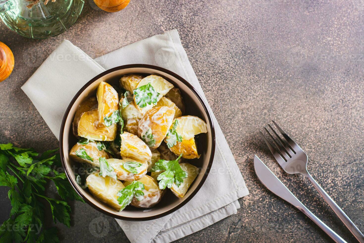 Potato salad in a peel with parsley and mayonnaise in a bowl on the table top view photo