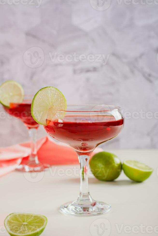 Close up of cosmopolitan cocktail with lime in glasses on the table top  view Stock Photo by Aleruana