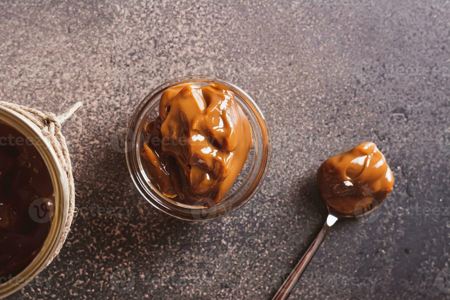 Close up of boiled sweet condensed milk in bowl and spoon on table top view photo