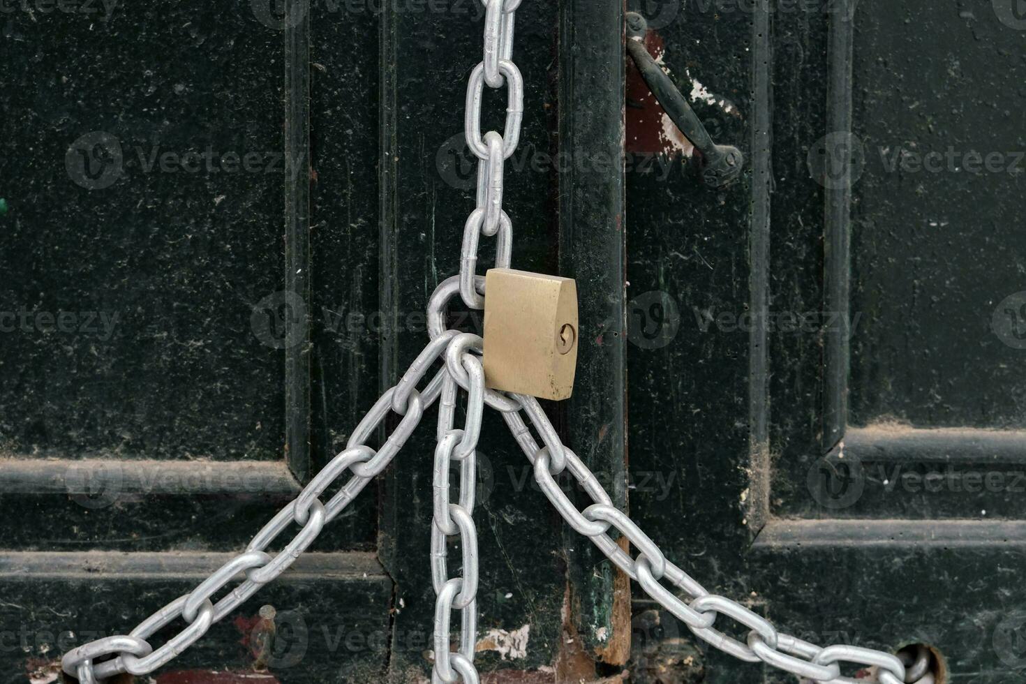 Metal padlock securing a chain at a wooden door photo