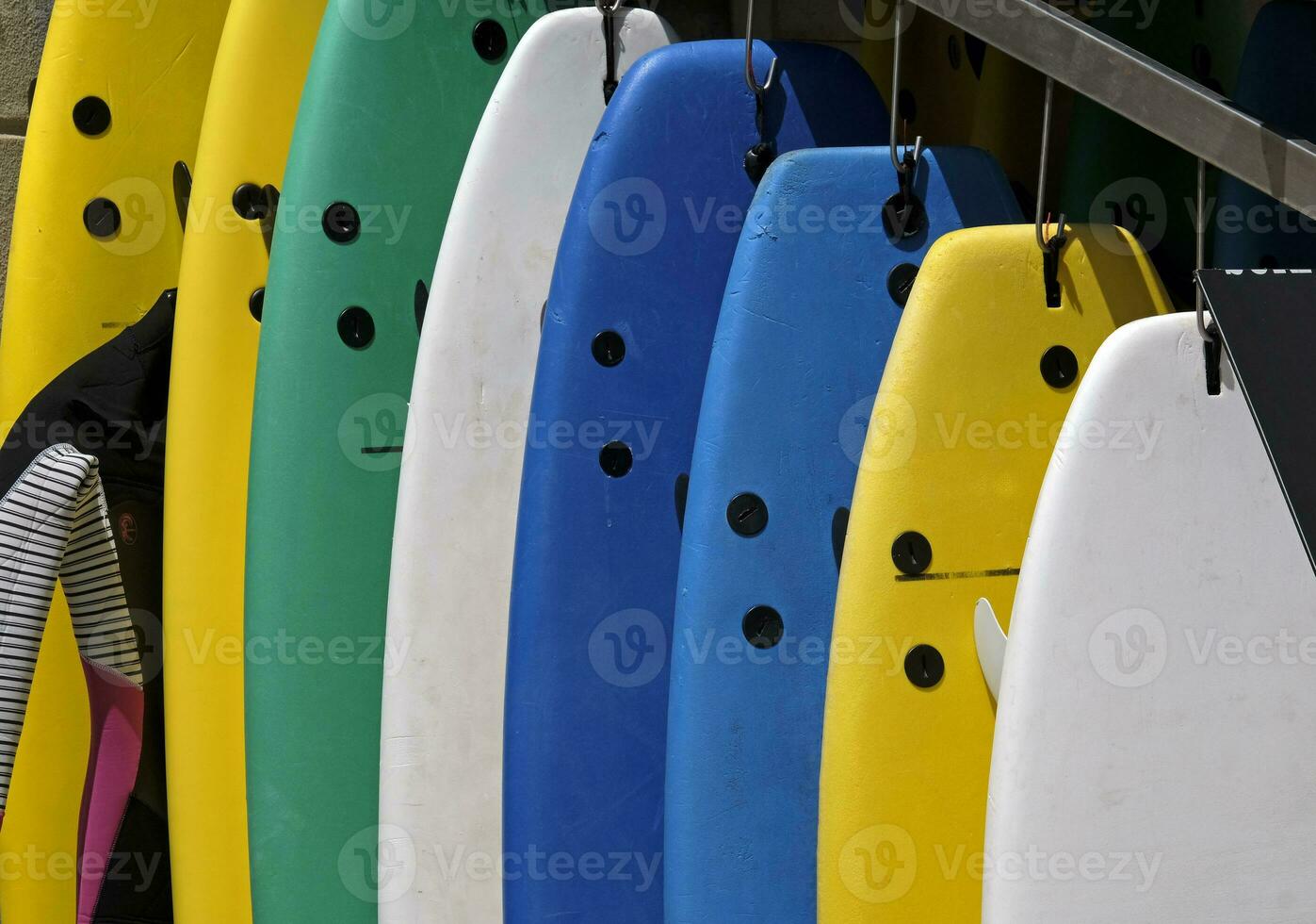 Multiple colorful surfboards hanging in front of a surfboard rental place in Ericeira, Portugal photo