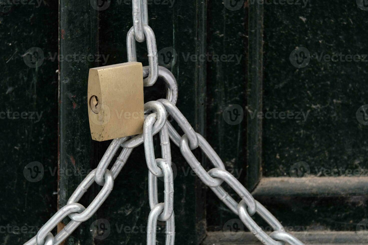 Metal padlock securing a chain at a wooden door photo