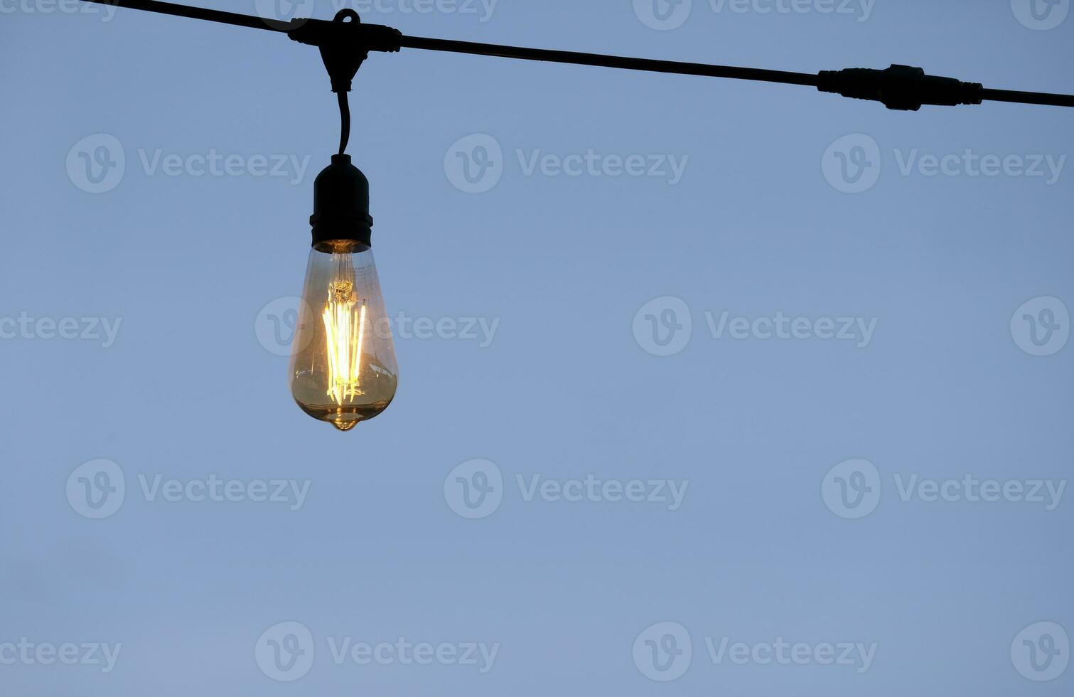 Single light bulb against a clear sky photo
