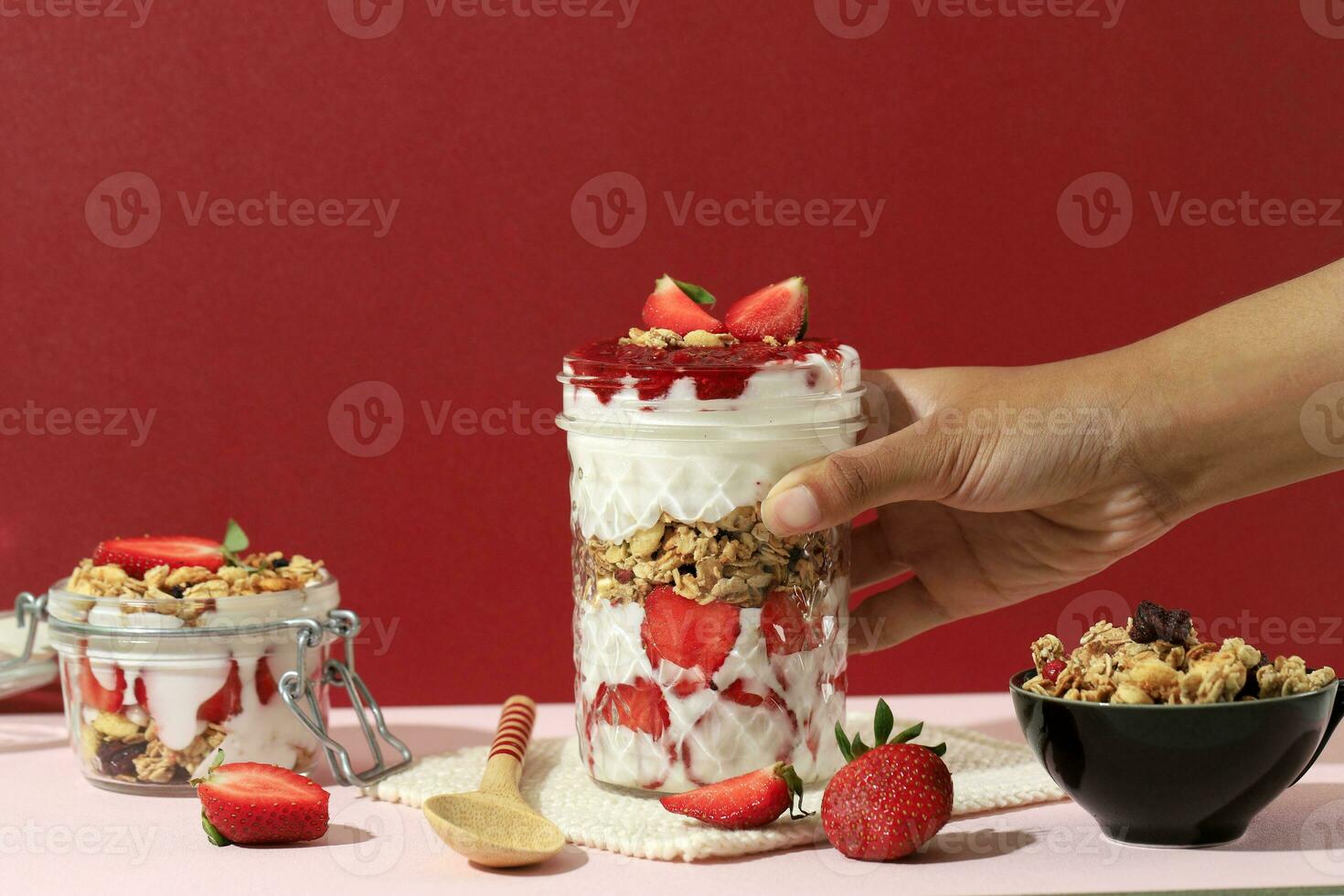 Female Hand Hold Drinking Jar with Strawberry Yoghurt Parfait photo