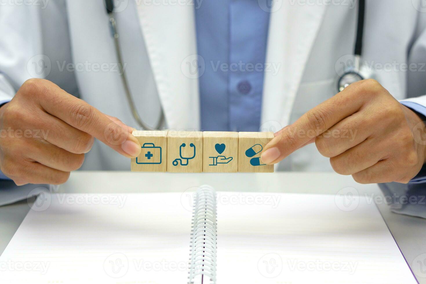 Focus on wooden block, hand of doctor holding a wooden block cube with healthcare medical icon symbol and below, there is a blurred book placed. Medical and health concept. photo