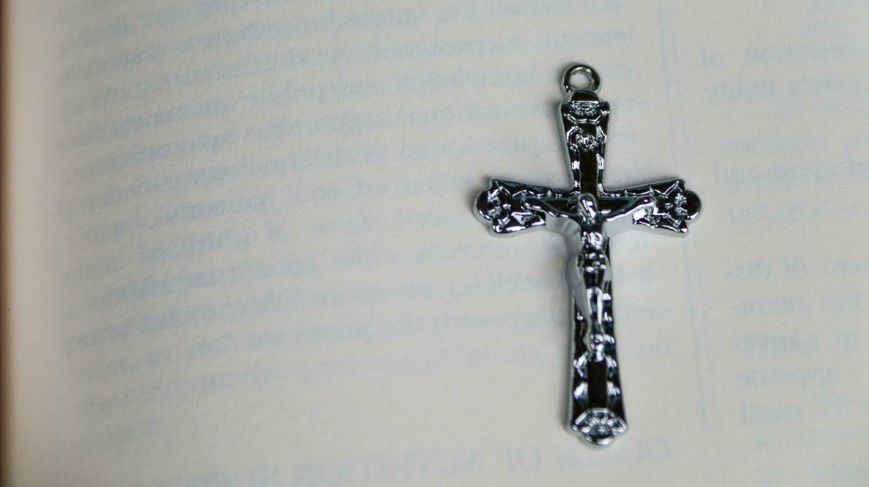 Close up shiny metal cross with black sling on old book to recall the kindness of Jesus Christ for all of Christian photo