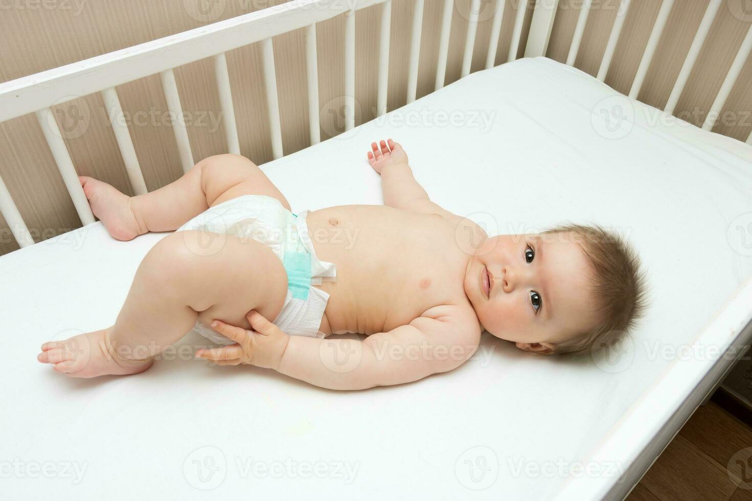 adorable baby girl lies in her crib, top view photo