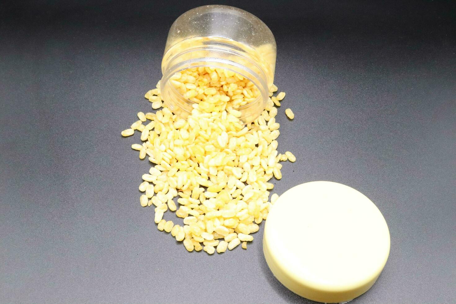 A pile of yellow small round Moong Dal Namkeen on black background,spicy and crispy namkeen dal,tea time snack,organic salty mong dal in glass jar photo