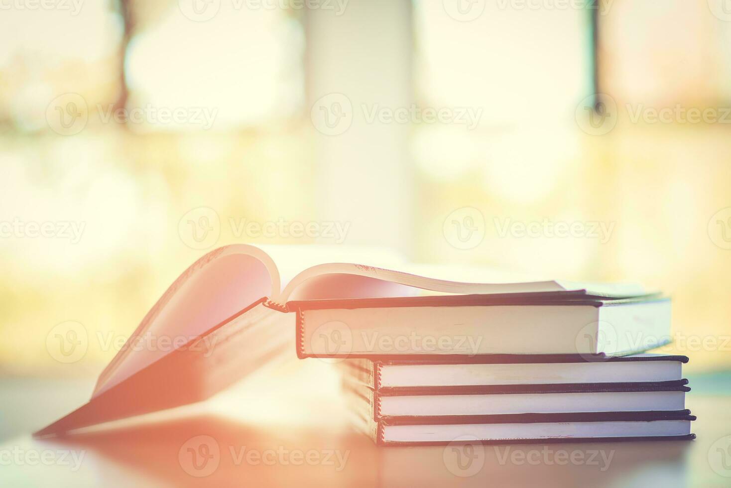 Pile of old books on the table with sunlight and copy space, Stack and one open book, Education learning concept. photo