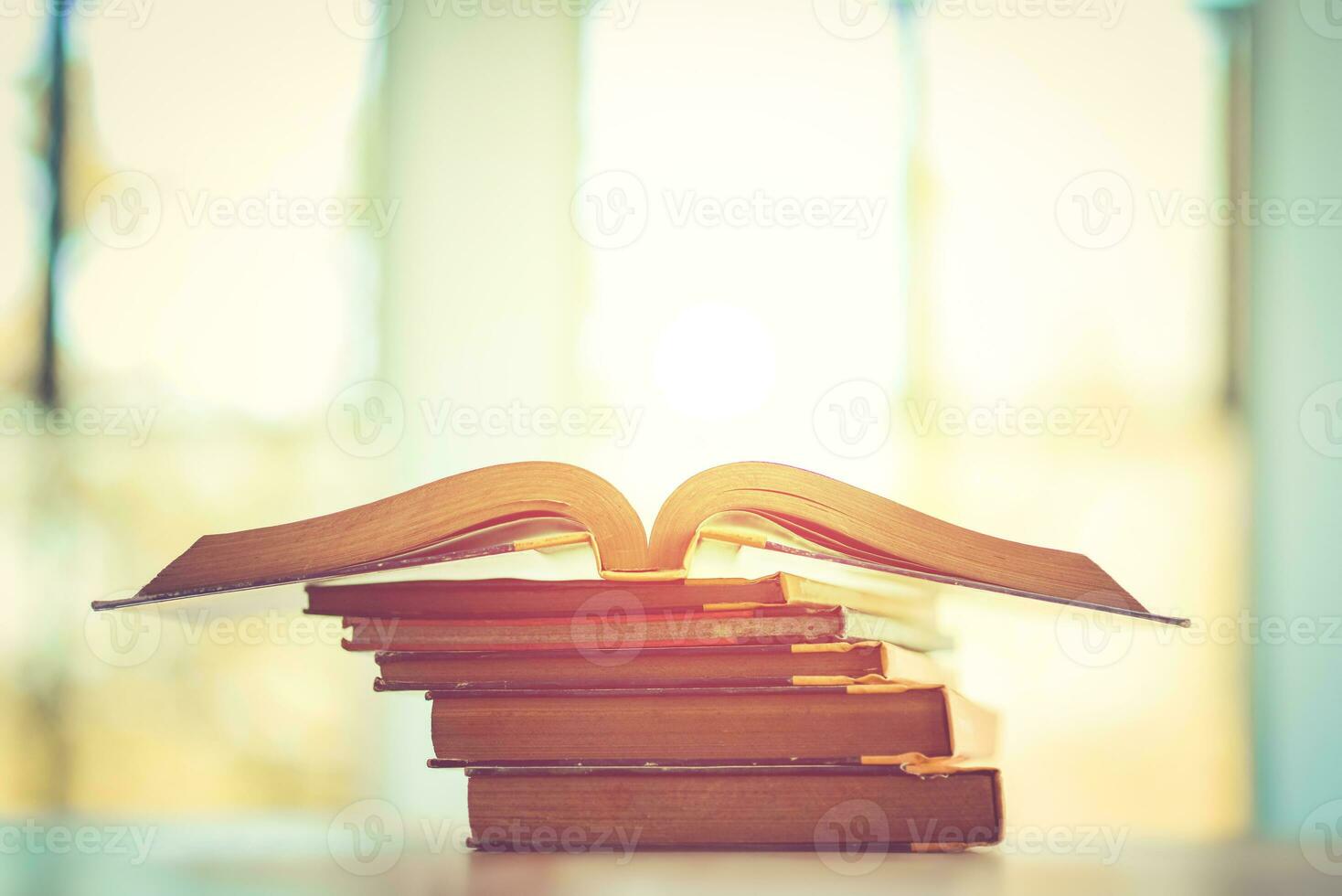 Pile of old books on the table with sunlight and copy space, Stack and one open book, Education learning concept. photo
