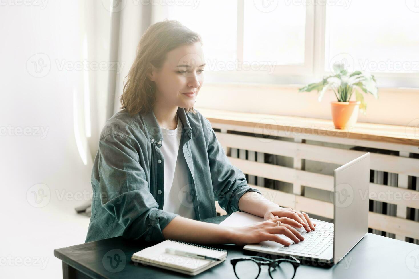 joven mujer utilizando ordenador portátil computadora en un moderno oficina ajuste y estudiante niña trabajando desde el comodidad de hogar. en línea trabajar, estudiar, Lanza libre, negocio, y oficina estilo de vida concepto foto