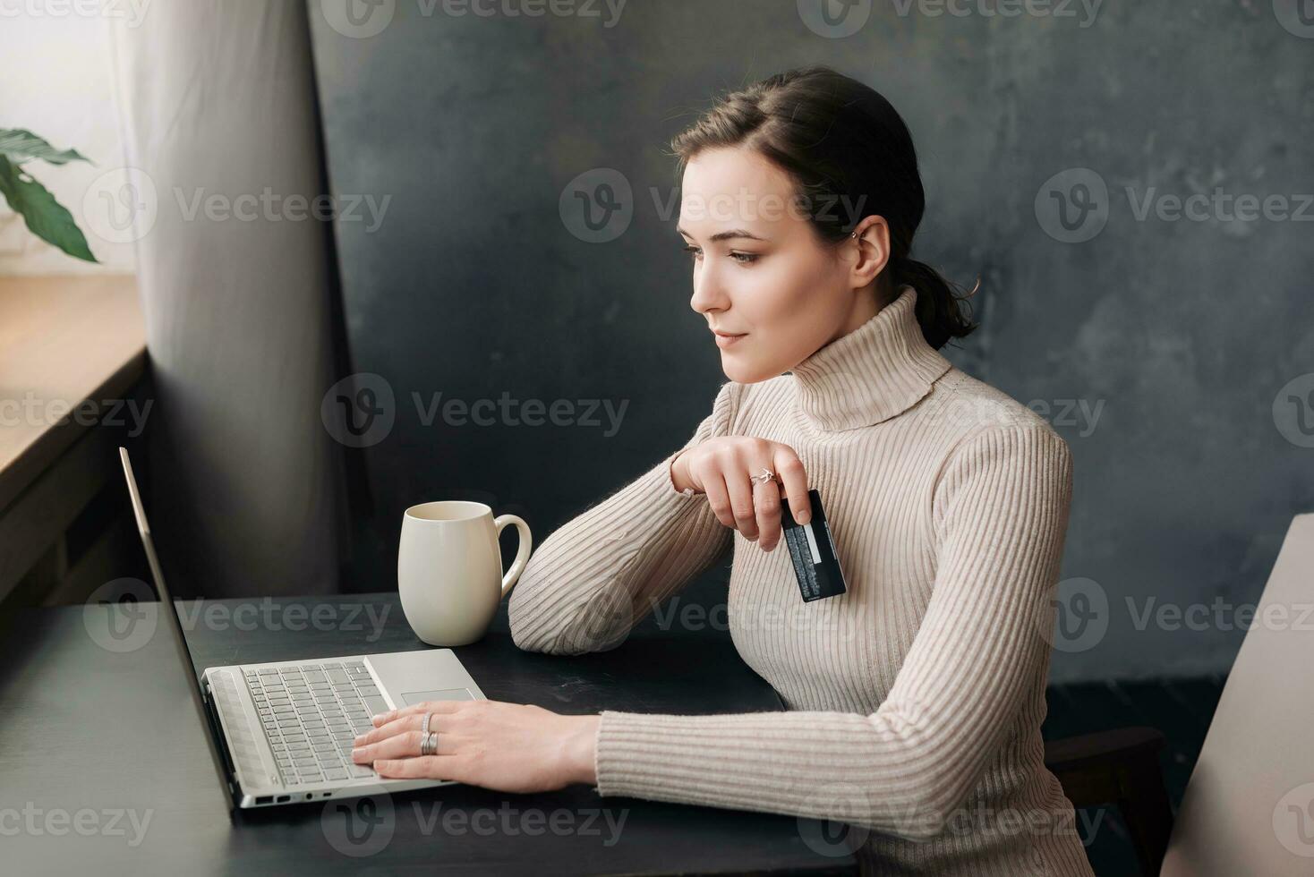 E-Commerce Lifestyle. Young Woman Shopping Online Using Credit Card and Laptop - Capturing the Digital Consumer Experience at Home photo