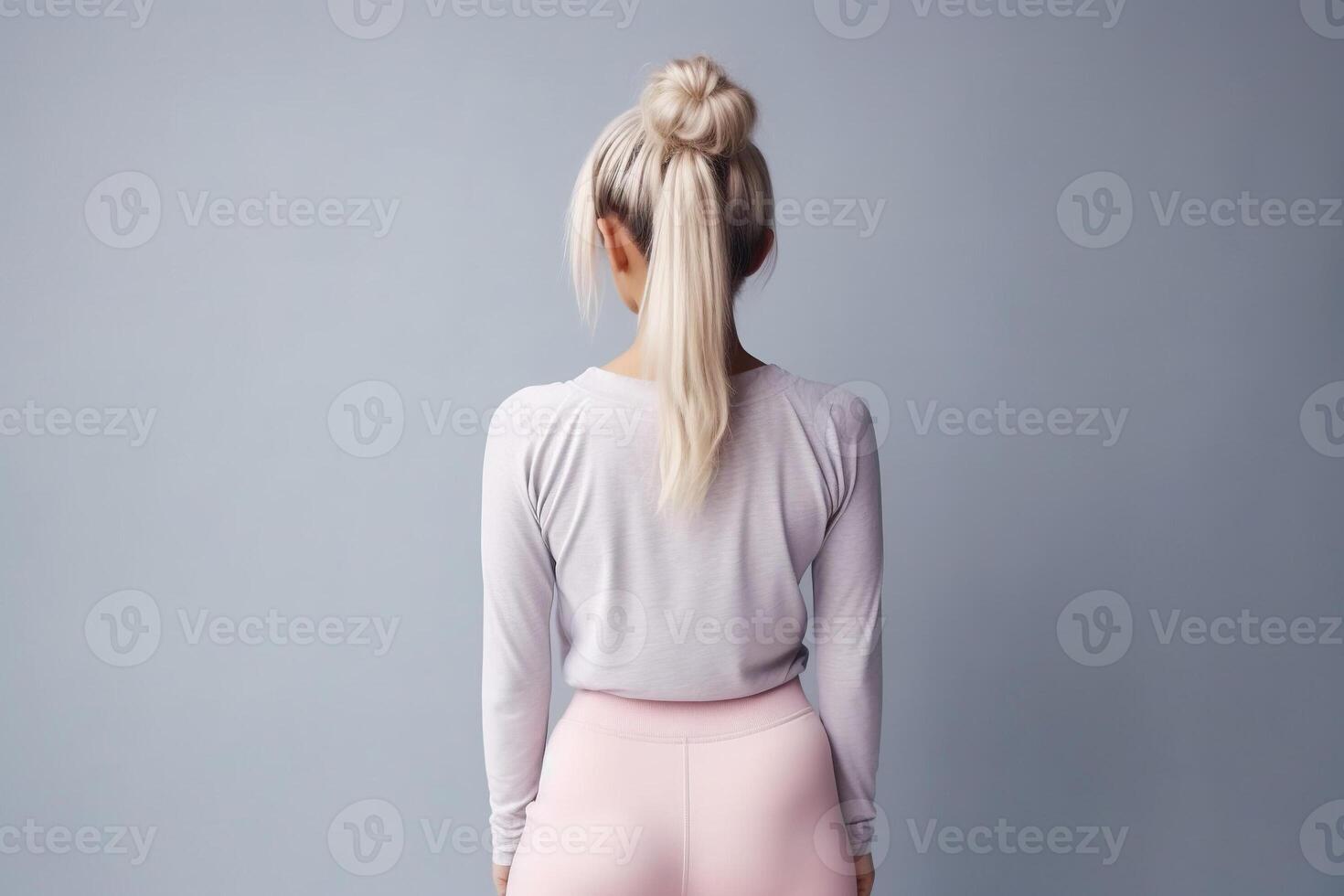 Rearview of a body confident woman standing in a studio, wearing sportswear on studio clean background. photo