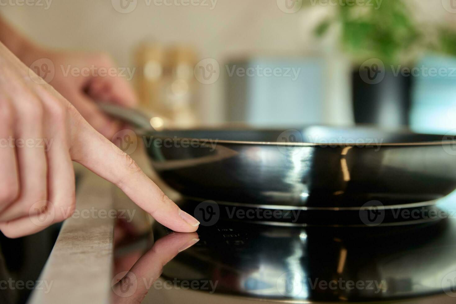 Woman turn on induction hob with frying pan photo