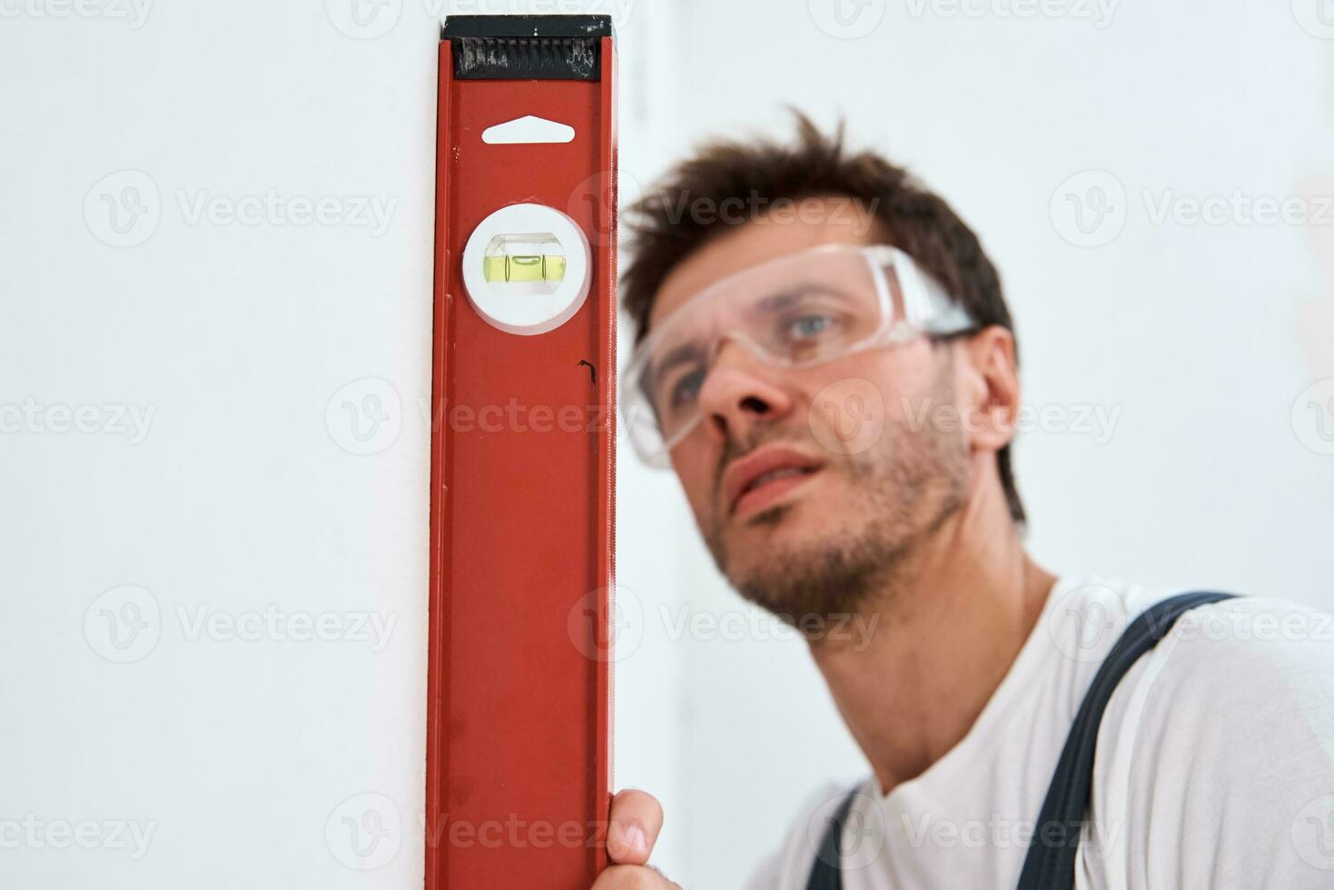 Renovation concept. Male worker checking level of the wall with the bubble level tool photo