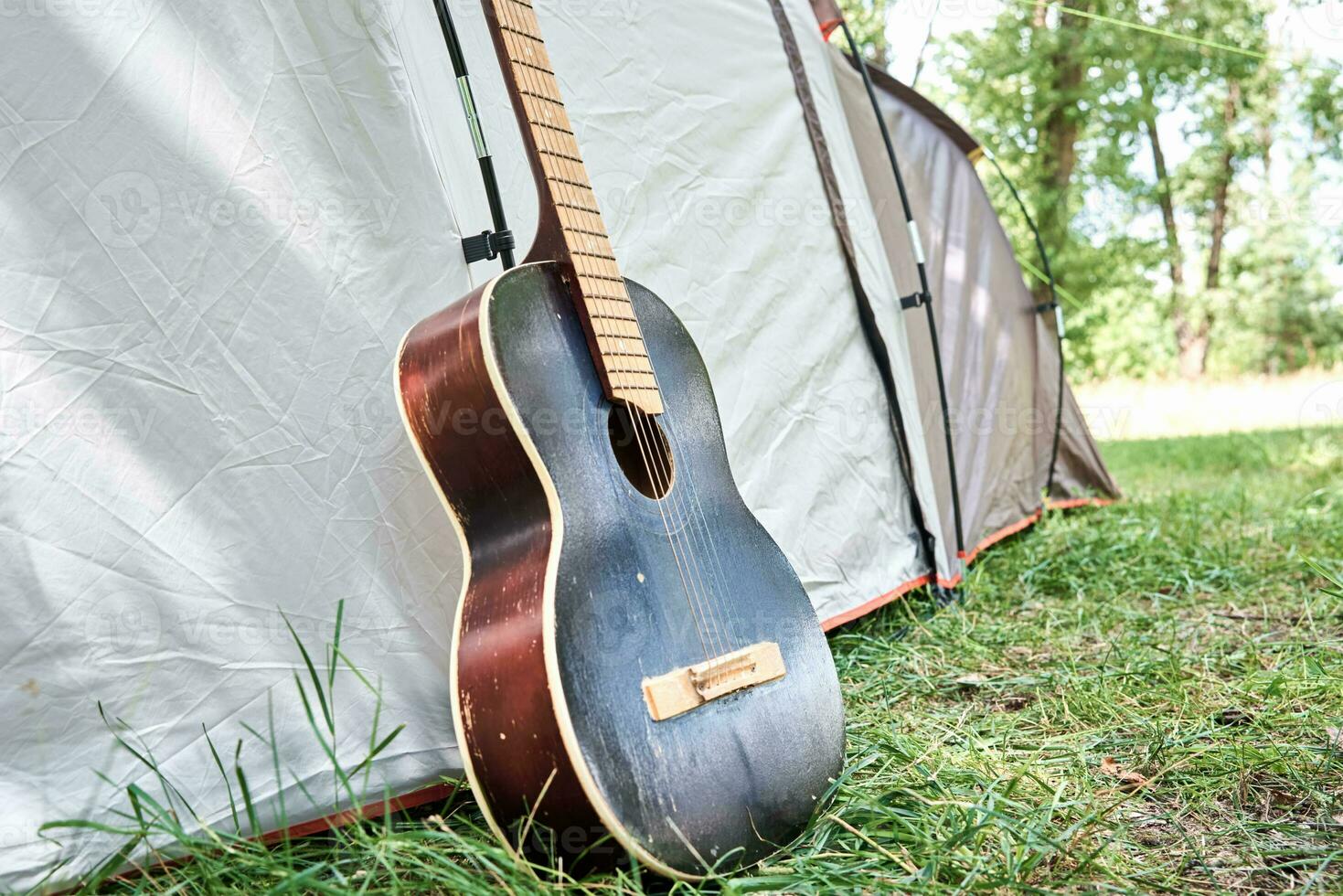 Acoustic guitar near a camping tent in forest photo