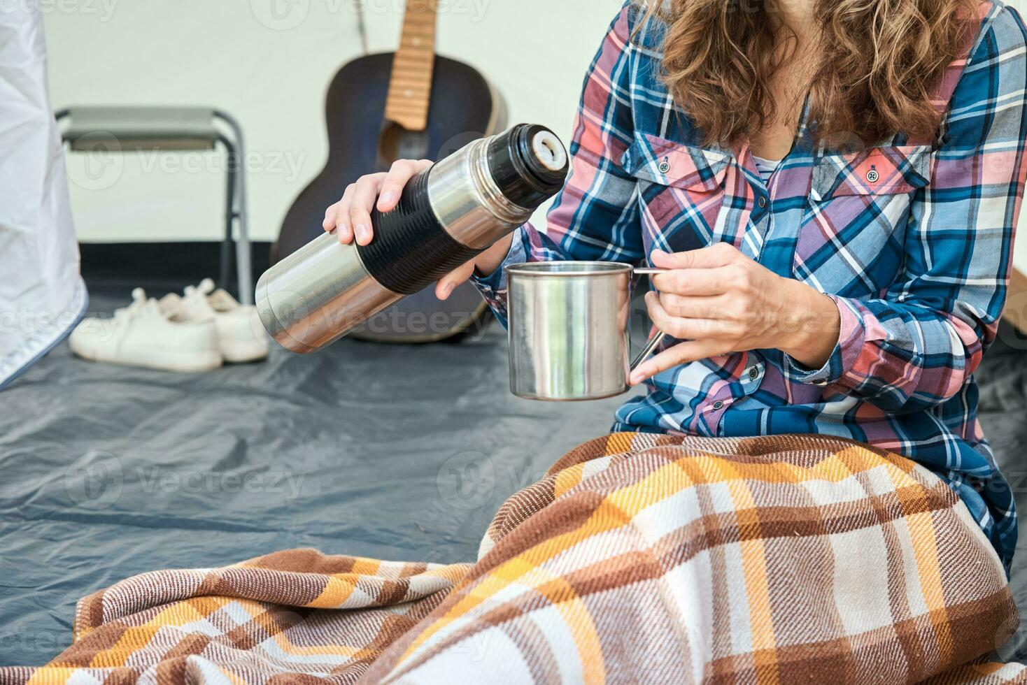 Woman pouring tea from thermos in the camping tent photo