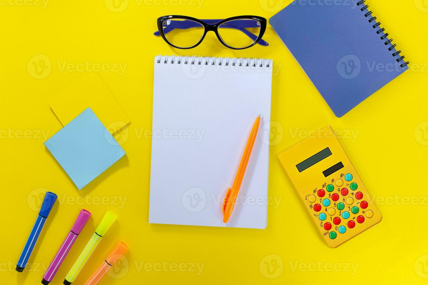 Notebook with pen, markers and stickers with calculator and glasses on yellow background. Back to school, business meeting. Copy space photo