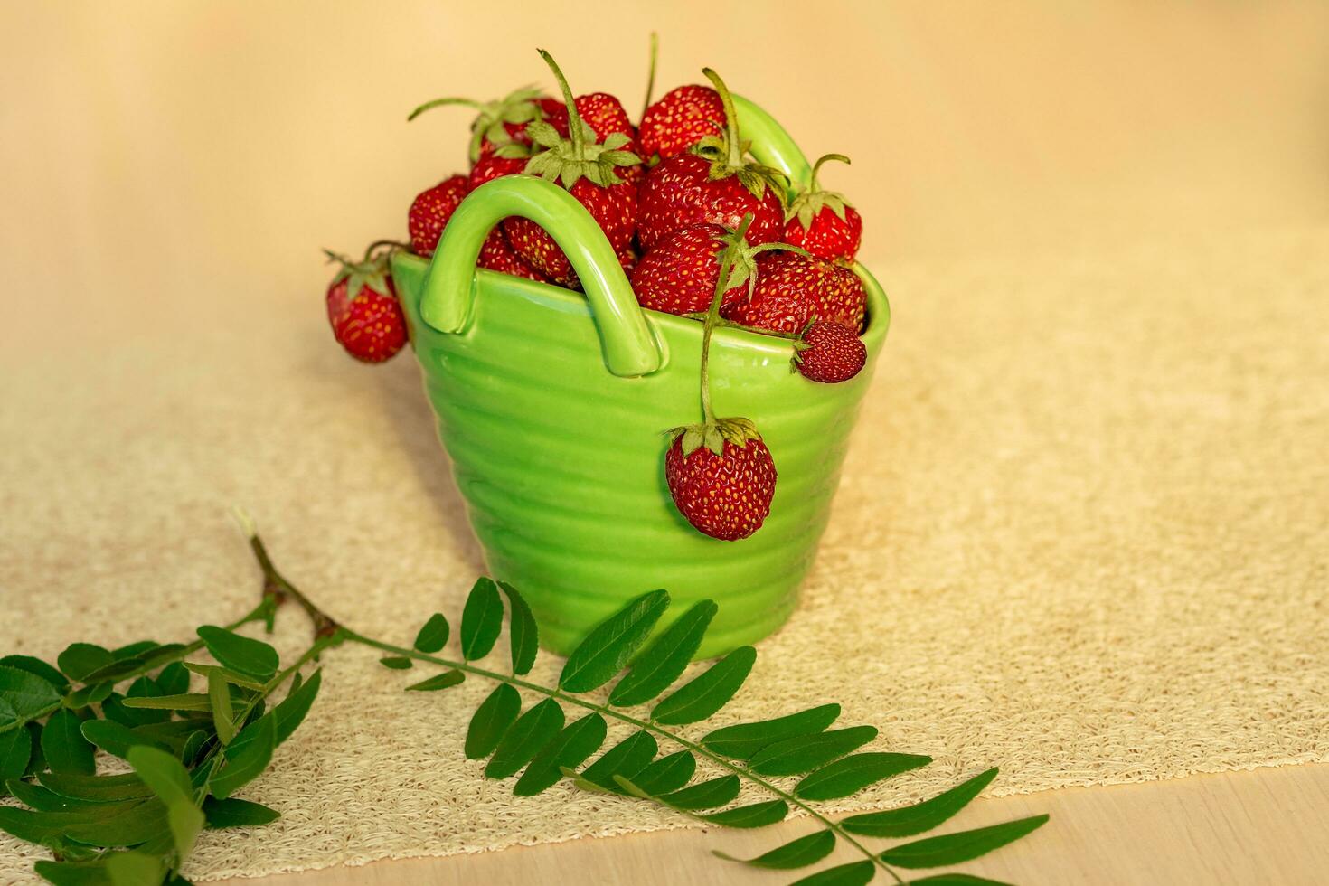 Red strawberries in a green porcelain basket with branch photo