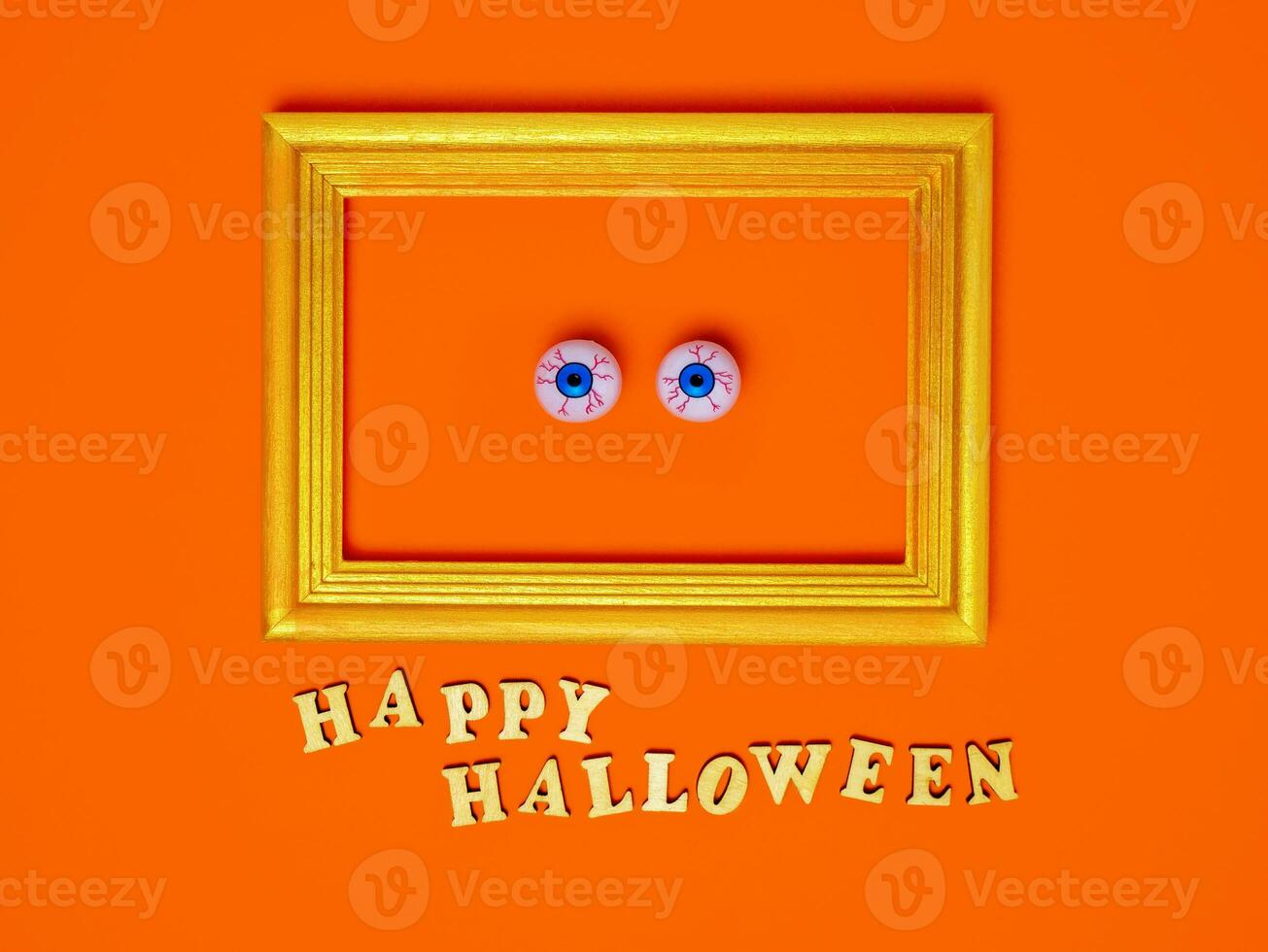 Scary and funny eyes in a frame, happy Halloween inscription on an orange background, copy space, Flat layout, top view photo