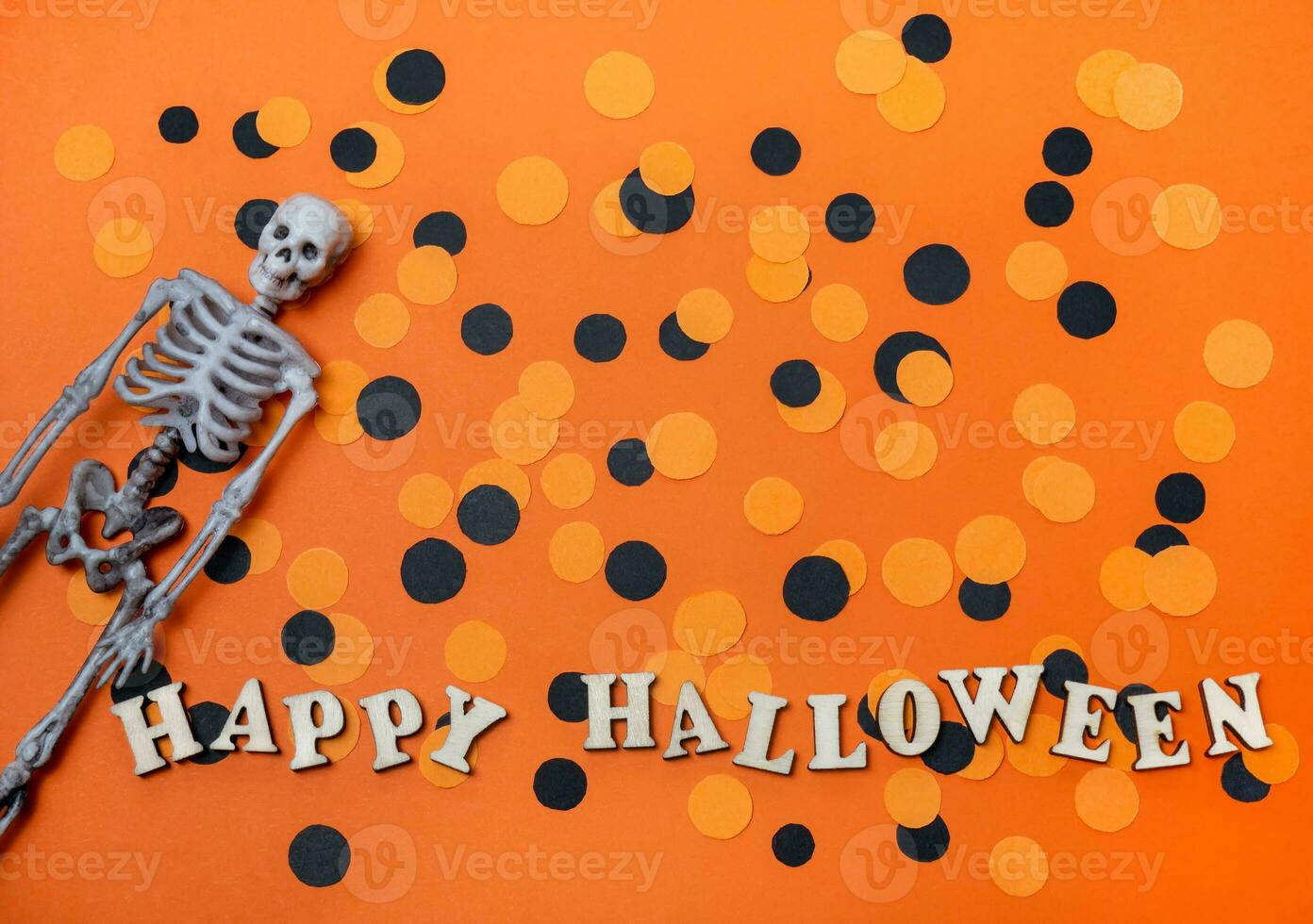 Halloween decorations on an orange background. Skeleton and confetti, Happy halloween inscription photo