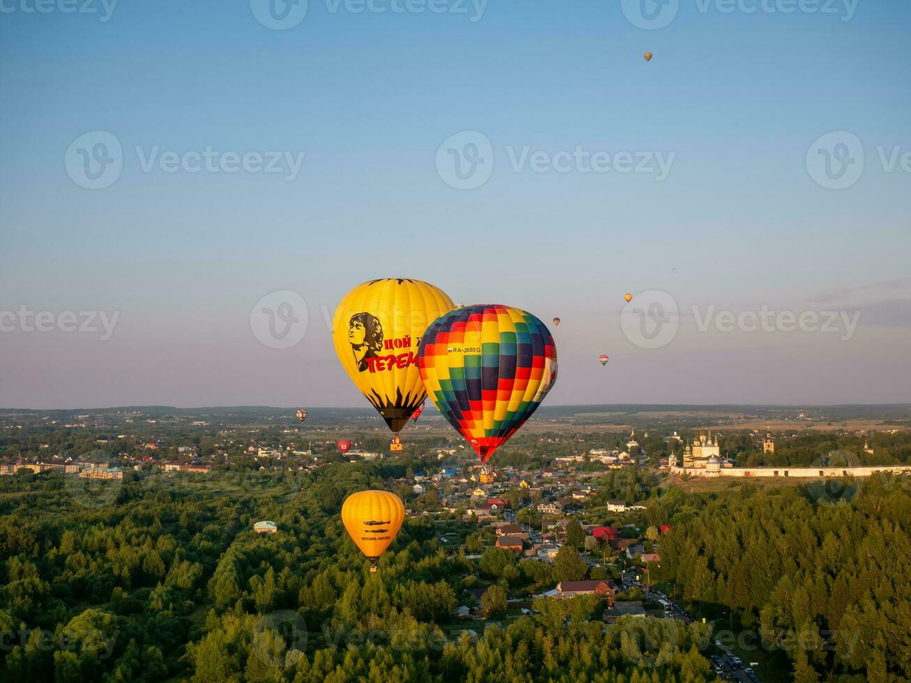 July 23, 2022 Russia, Pereslavl-Zalessky. Aeronautics festival, big balloons with baskets flying over houses and church photo