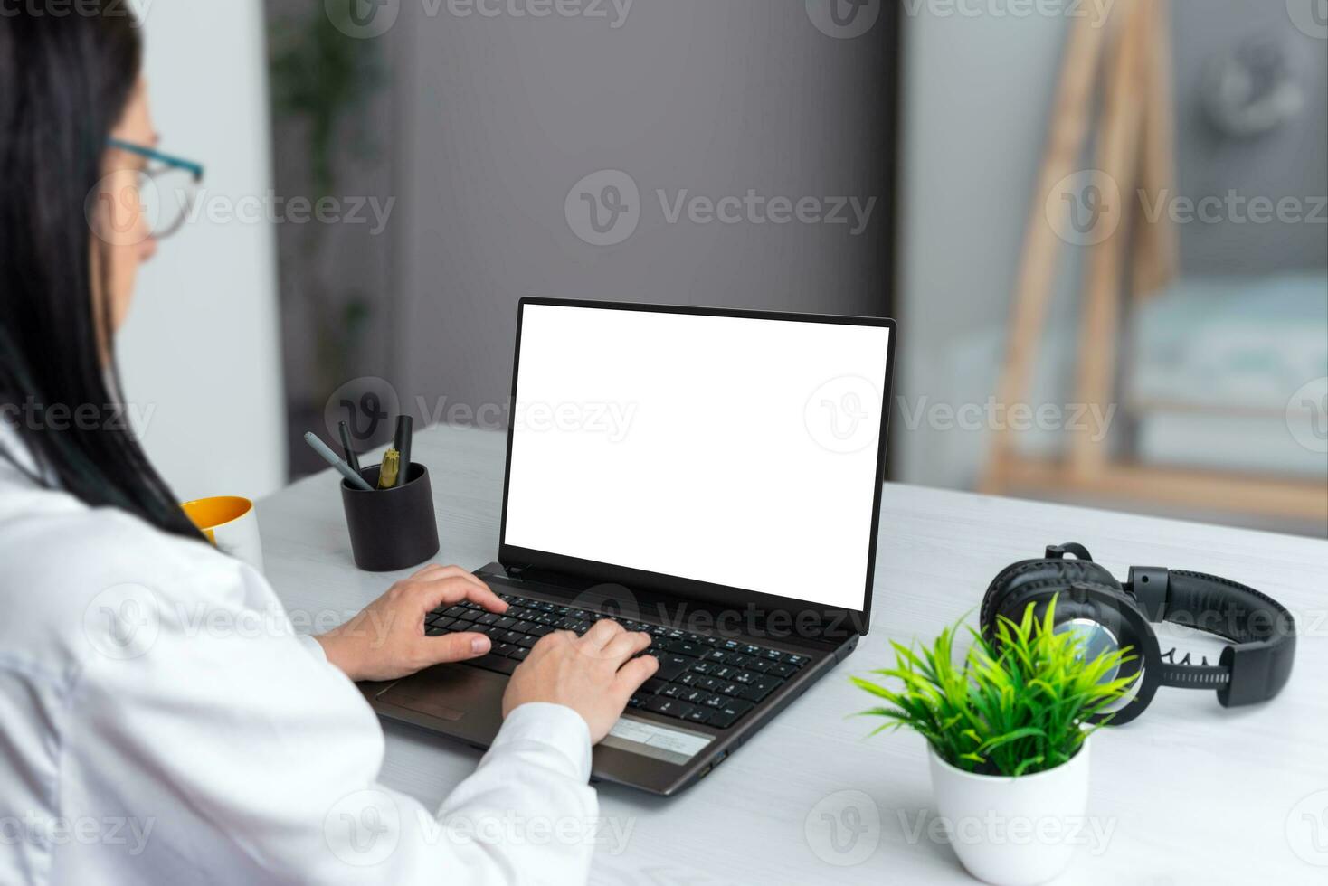 A focused girl works on a laptop with an isolated screen for mockup. Business scene on an office desk photo