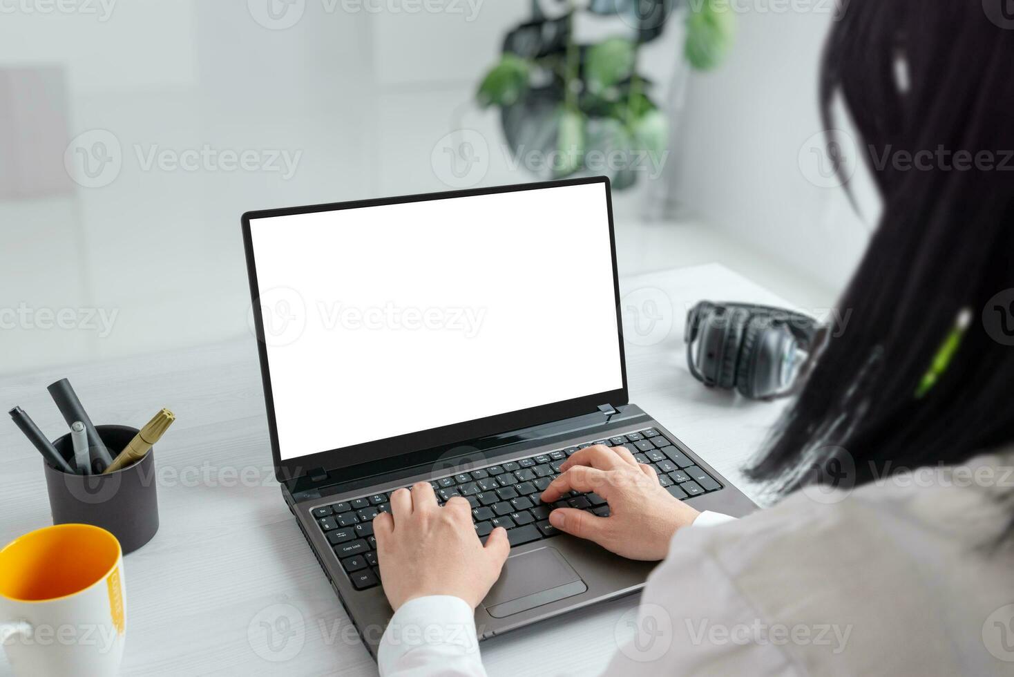 Girl immersed in her tasks on a laptop with an isolated screen for mockup. Professional office desk composition photo