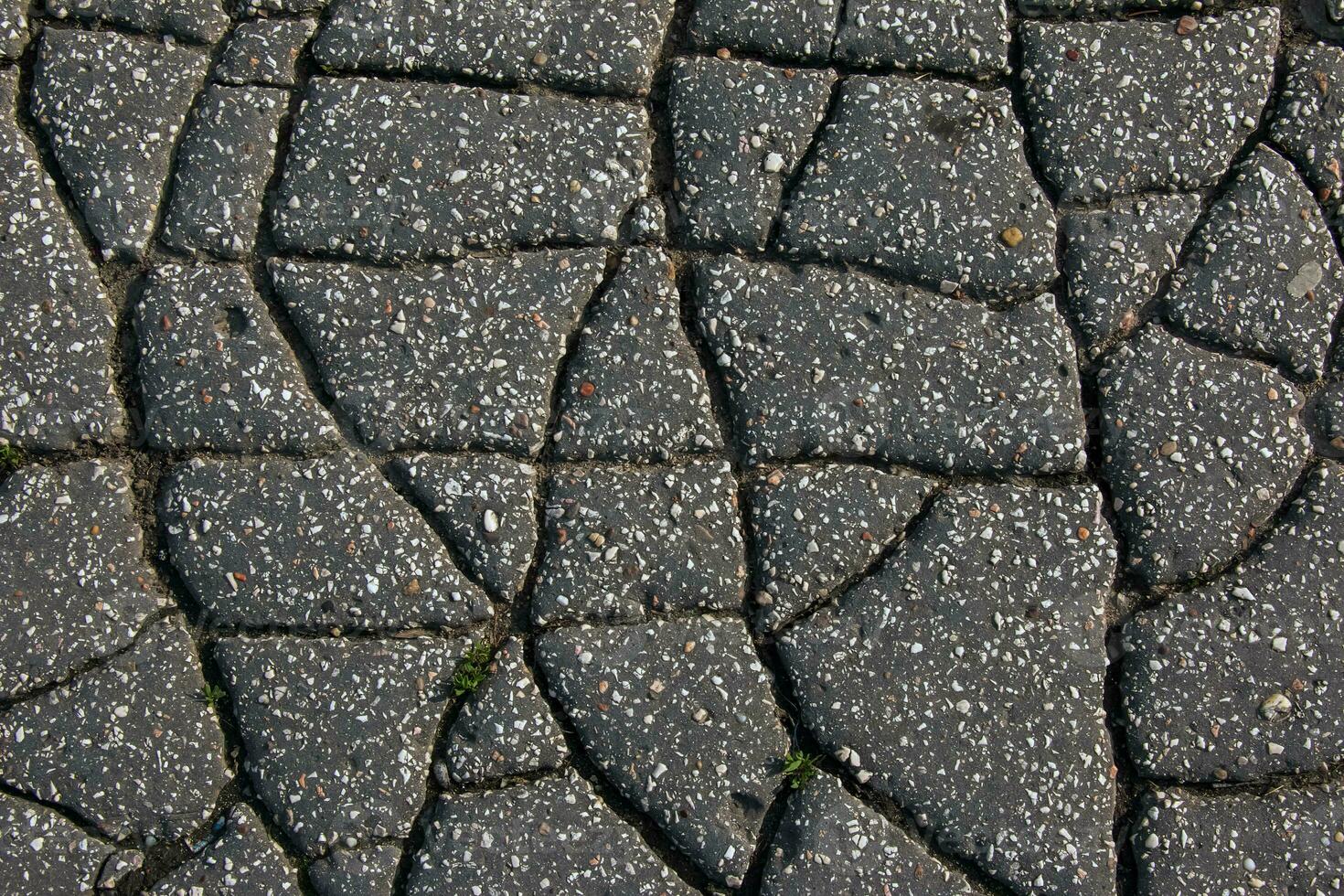 A network of black cracks on the asphalt surface. Road texture with weathered surface, showcasing the effects of time and wear. photo