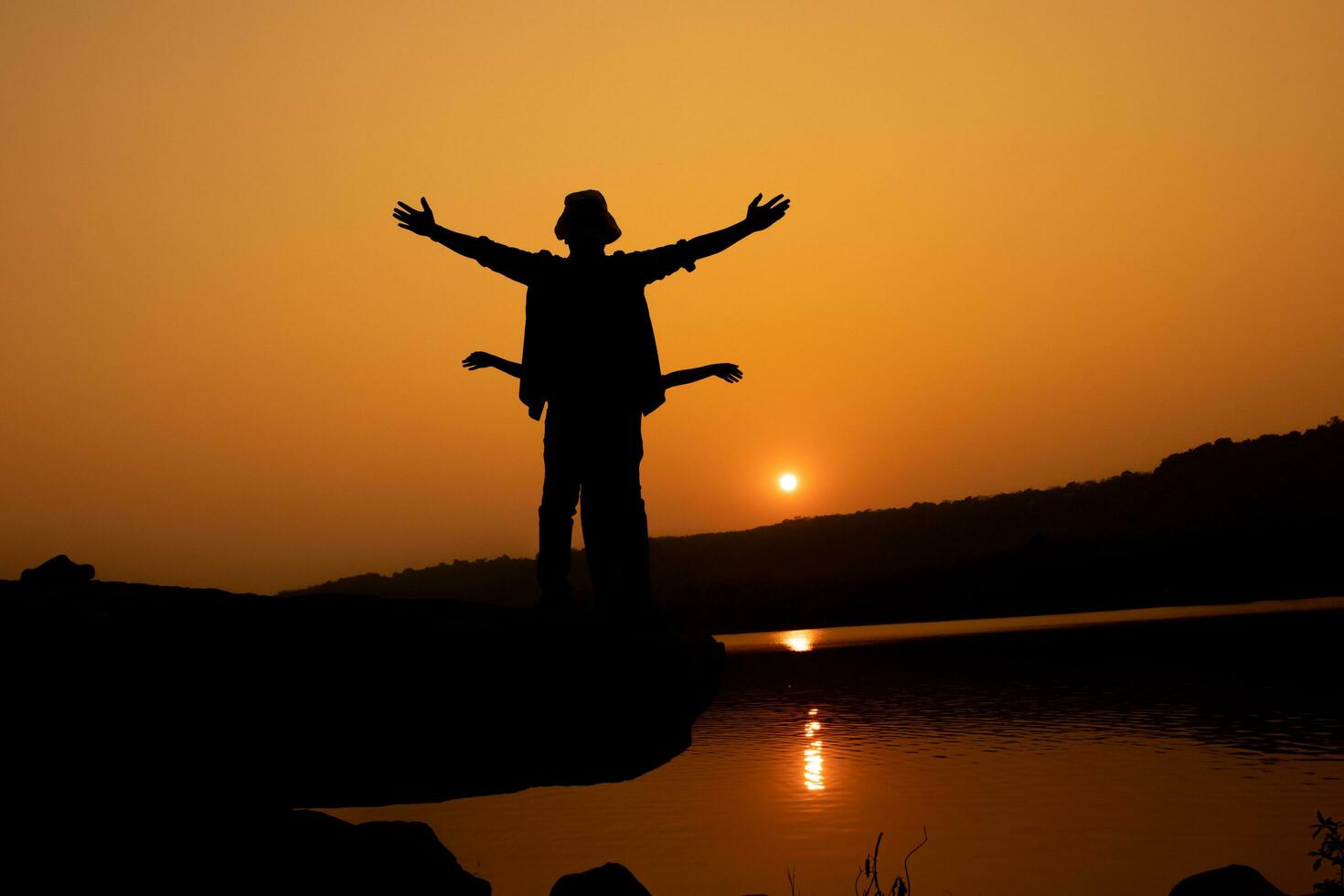 Silhouette of a person on a rock near the reservoir photo