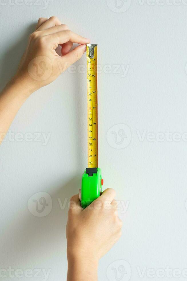 Man hand using tape measure for measuring with wall backgrounds at home. DIY, Interior design, repairing and improvement home or apartment concepts photo