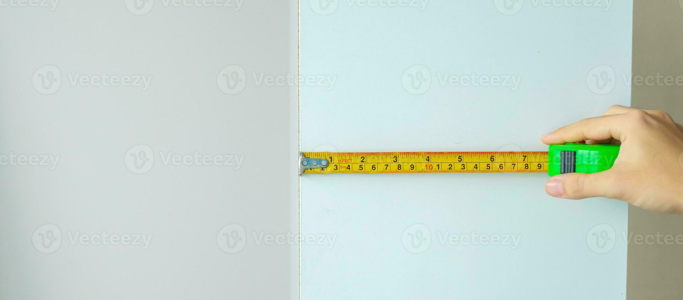 Man hand using tape measure for measuring furniture at home. DIY, Interior design, repairing and improvement home or apartment concepts photo