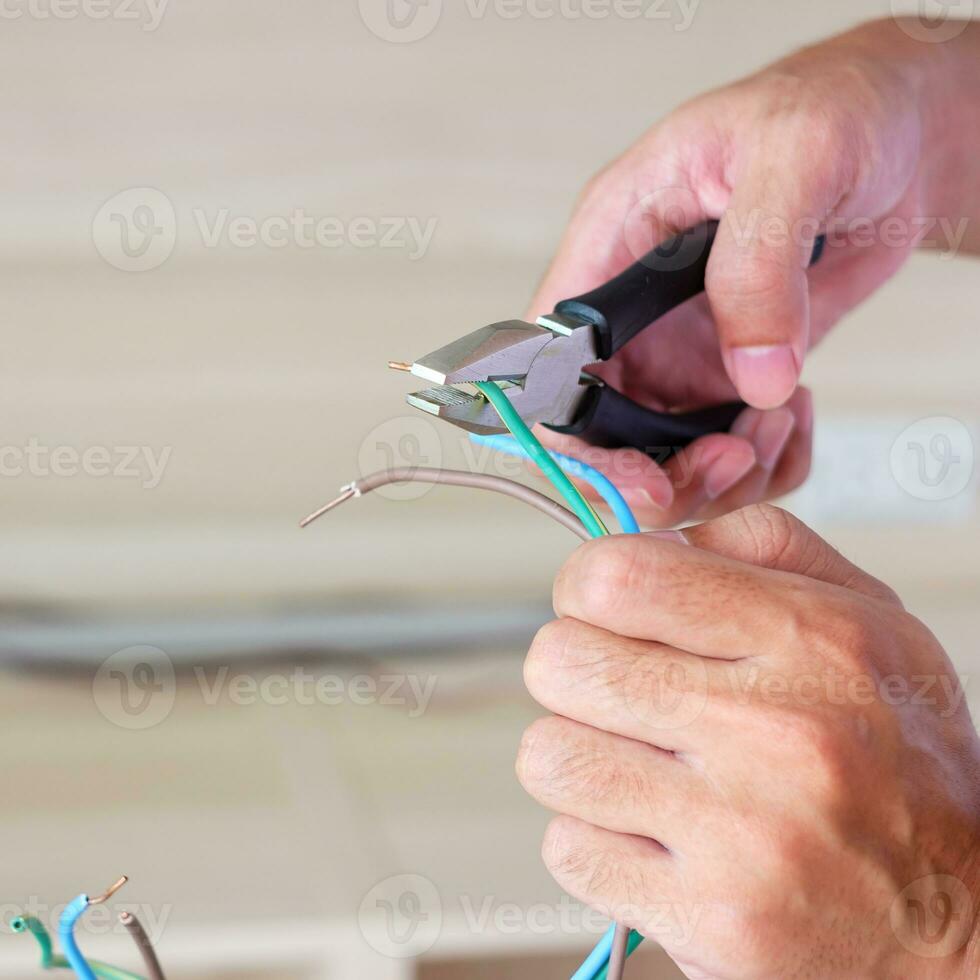 Electrician cuts electrical wires with pliers, Wiring cables installation for socket plug. Fixing, Renovation, Repair, service and development of home and apartment concepts photo