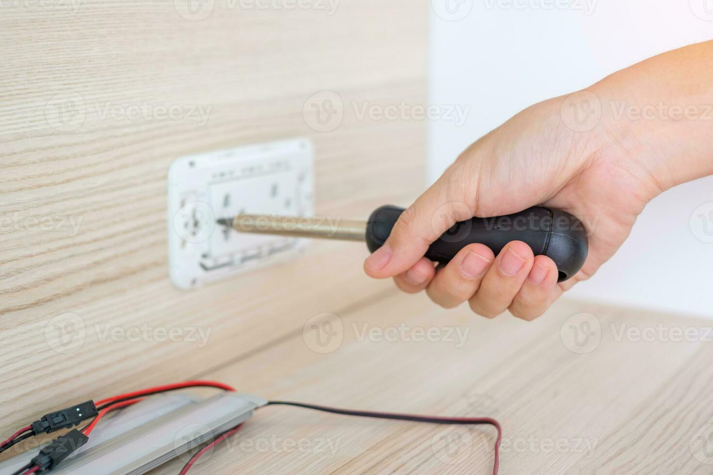 Man hand using screwdriver installing Wire cables for socket plug. Renovation, Repair, fixing and development of home and apartment concepts photo