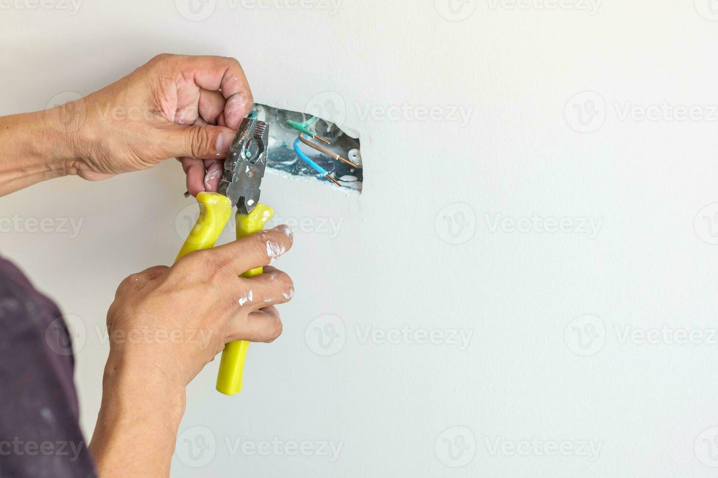 Electrician cuts electrical wires with pliers, Wiring cables installation for socket plug to a concrete. Renovation, Repair, service and development of home and apartment concepts photo