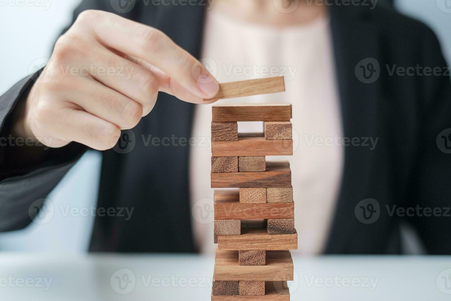 Businesswoman hand placing or pulling wooden block on the tower. Business planning, Risk Management, Solution and strategy Concepts photo