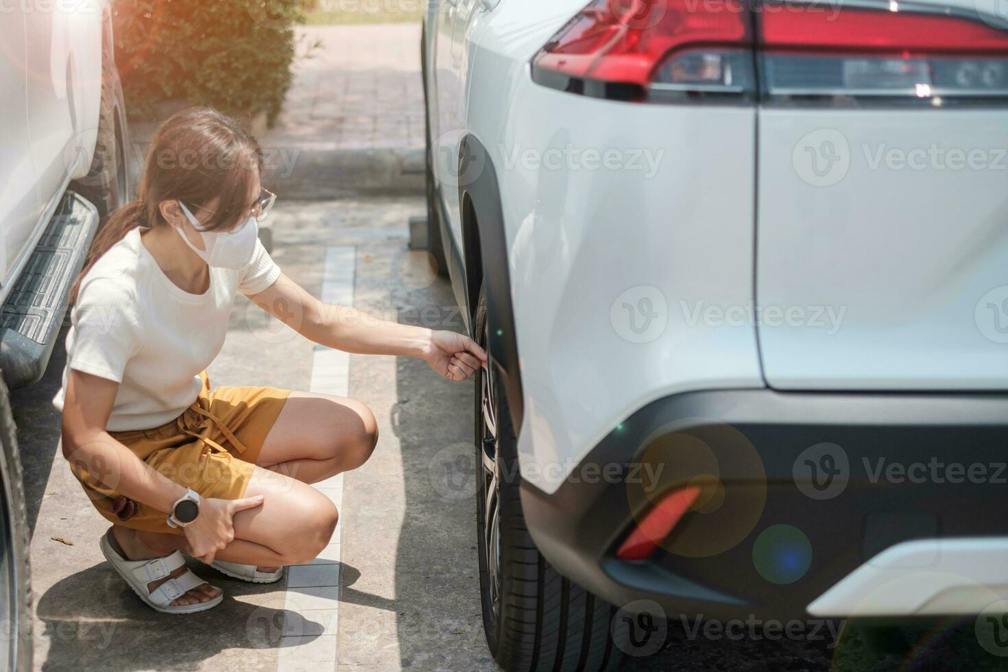 Woman driver hand inflating tires of vehicle, removing tire valve nitrogen cap for checking air pressure and filling air on car wheel at gas station. self service, maintenance and safety photo