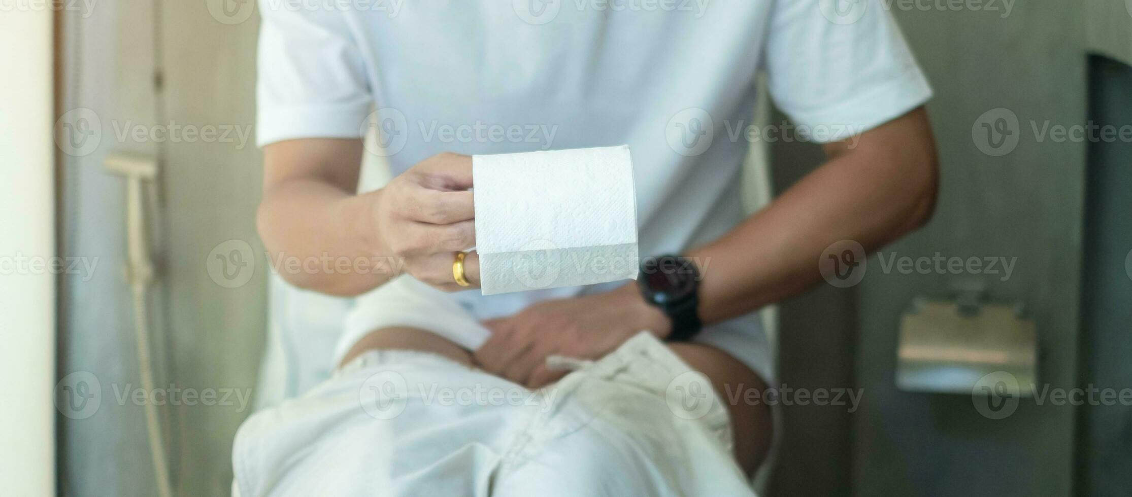 man holding toilet paper roll during sit on toilet bowl. diarrhea, constipated period, infection, abdominal, stomachache, cystitis, Insurance and Medical concept photo