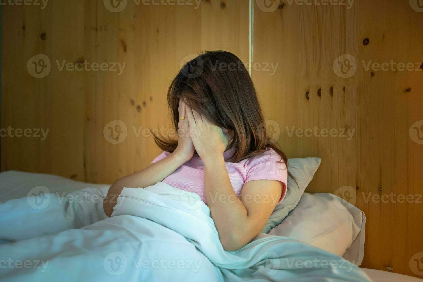 woman having migraine headaches during lying in bed at home. insomnia, sleepless, tired, suffering and stressed concepts photo