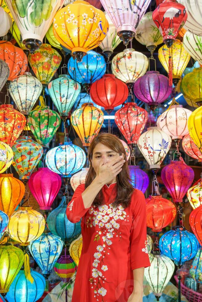 happy woman wearing Ao Dai Vietnamese dress with colorful lanterns, traveler sightseeing at Hoi An ancient town in central Vietnam.landmark for tourist attractions.Vietnam and Southeast travel concept photo