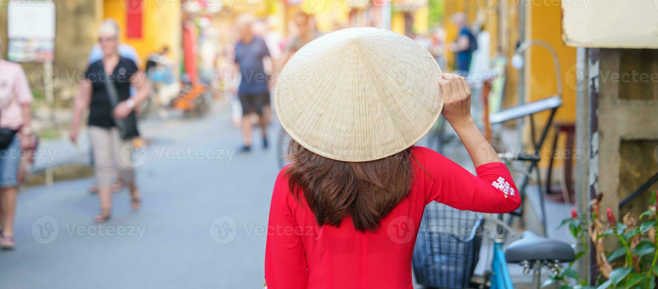 happy woman wearing Ao Dai Vietnamese dress, asian traveler sightseeing at Hoi An ancient town in central Vietnam. landmark and popular for tourist attractions. Vietnam and Southeast travel concept photo