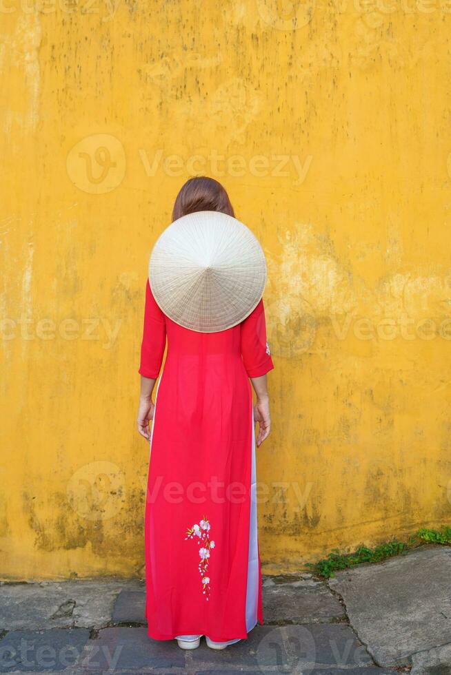 happy woman wearing Ao Dai Vietnamese dress and hat, traveler sightseeing at Hoi An ancient town in central Vietnam. landmark and popular for tourist attractions. Vietnam and Southeast travel concept photo