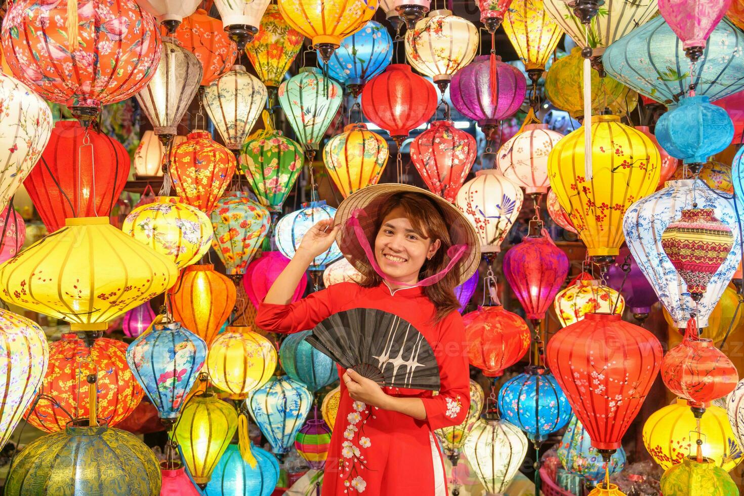 happy woman wearing Ao Dai Vietnamese dress with colorful lanterns, traveler sightseeing at Hoi An ancient town in central Vietnam.landmark for tourist attractions.Vietnam and Southeast travel concept photo