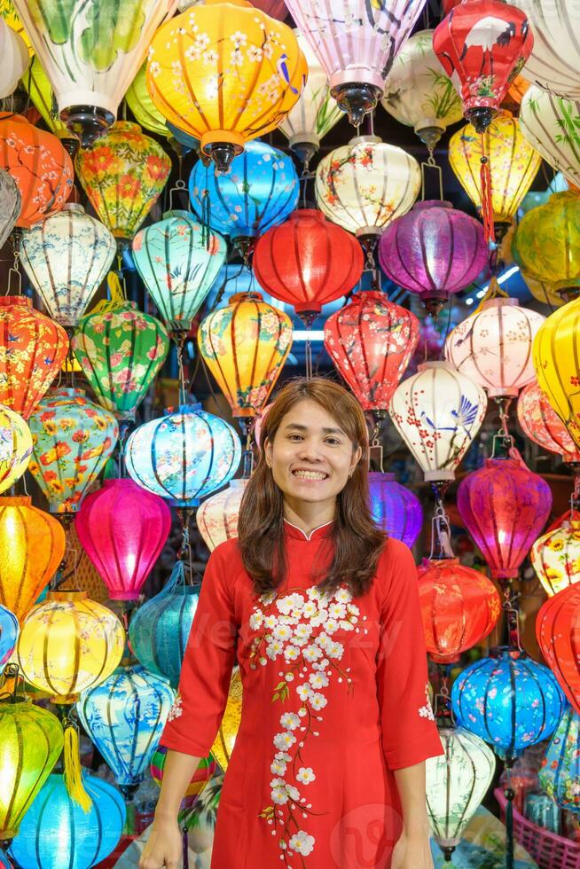 happy woman wearing Ao Dai Vietnamese dress with colorful lanterns, traveler sightseeing at Hoi An ancient town in central Vietnam.landmark for tourist attractions.Vietnam and Southeast travel concept photo