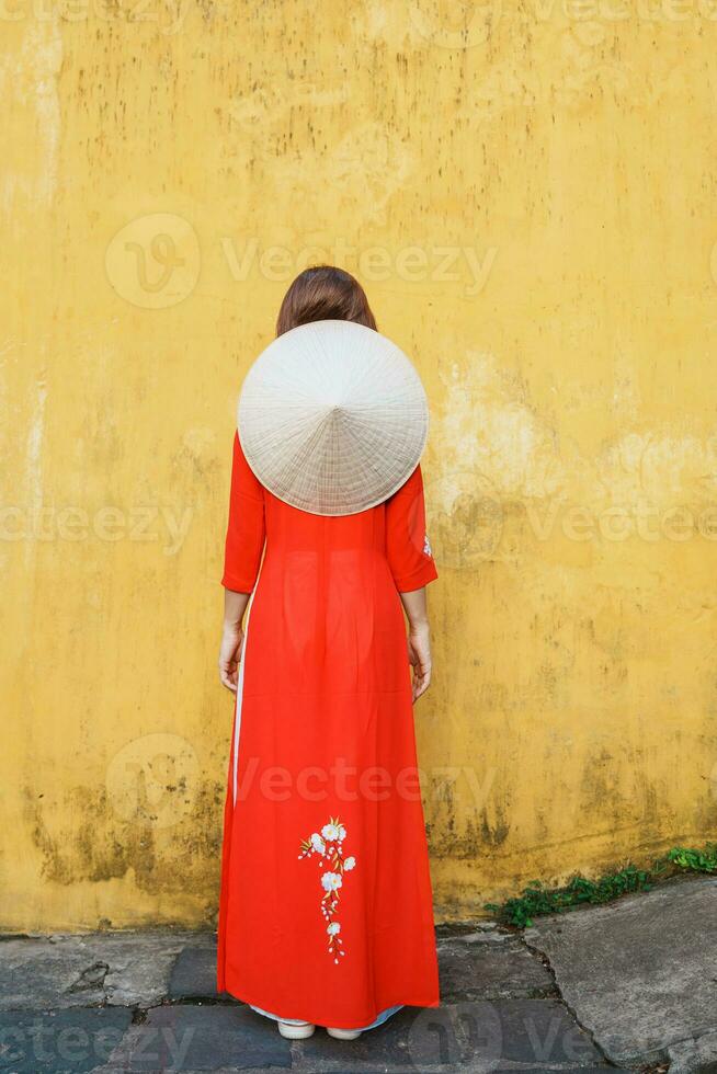 happy woman wearing Ao Dai Vietnamese dress and hat, traveler sightseeing at Hoi An ancient town in central Vietnam. landmark and popular for tourist attractions. Vietnam and Southeast travel concept photo