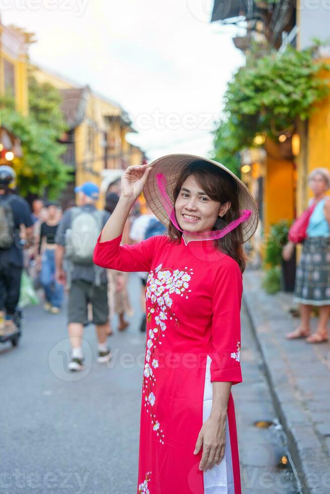 happy woman wearing Ao Dai Vietnamese dress, asian traveler sightseeing at Hoi An ancient town in central Vietnam. landmark and popular for tourist attractions. Vietnam and Southeast travel concept photo