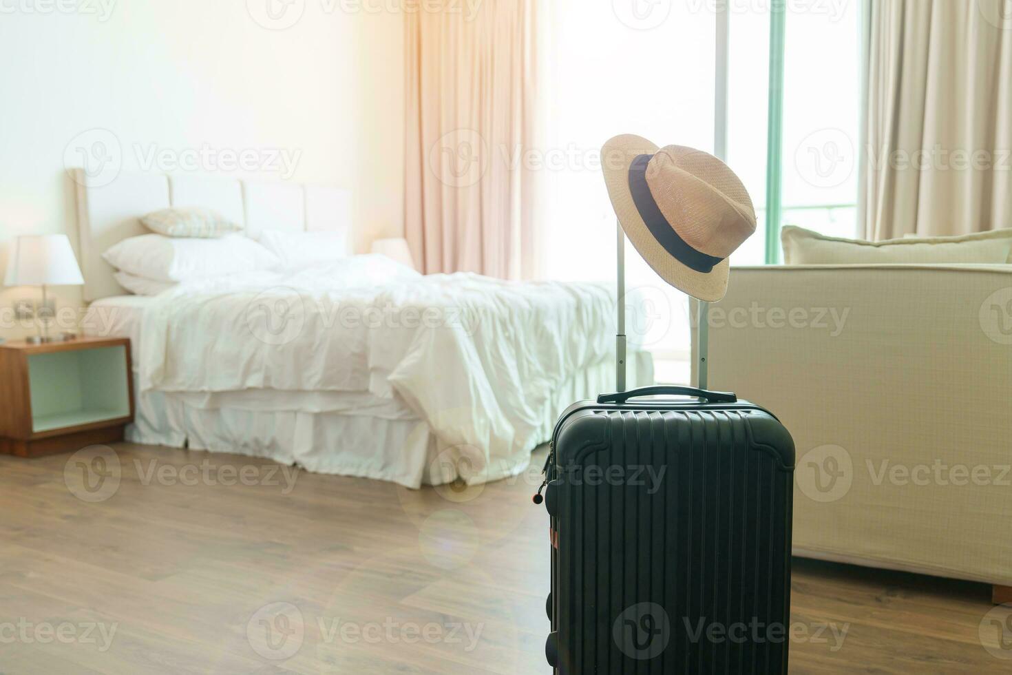 Black Luggage with hat in modern hotel room after door opening. Baggage for Time to travel, service, journey, trip, summer holiday and vacation concepts photo