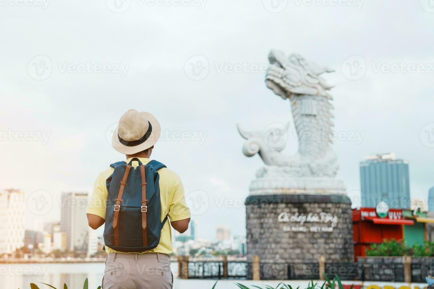 Solo Man Traveler with backpack in Da Nang. Tourist sightseeing the river view with Carp Dragon Statue or Ca Chep Hoa Rong.Landmark and popular. Vietnam and Southeast Asia travel concept photo